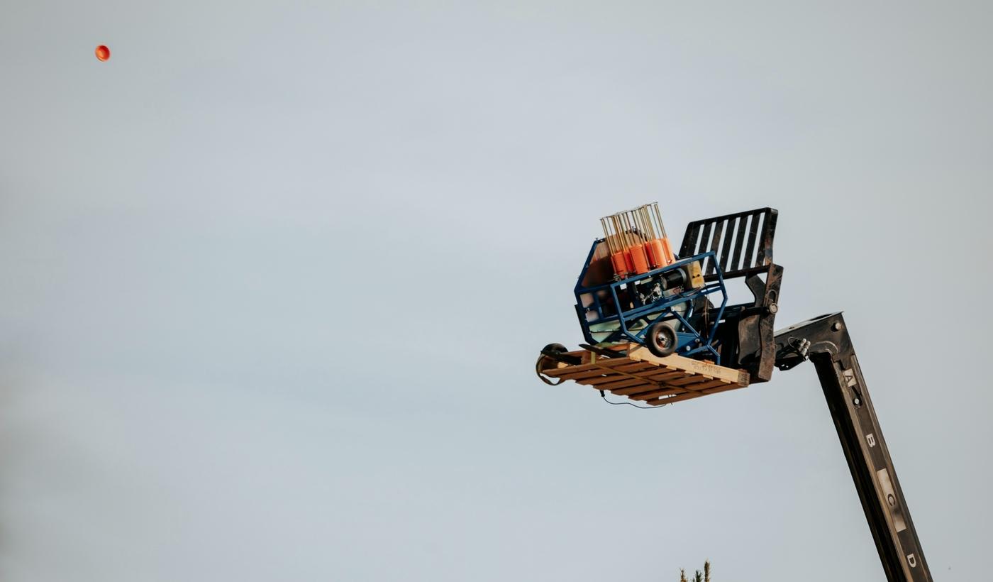 A hoisted clay target thrower throwing a clay target
